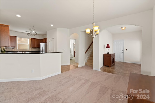 kitchen featuring stainless steel refrigerator, light colored carpet, and decorative light fixtures