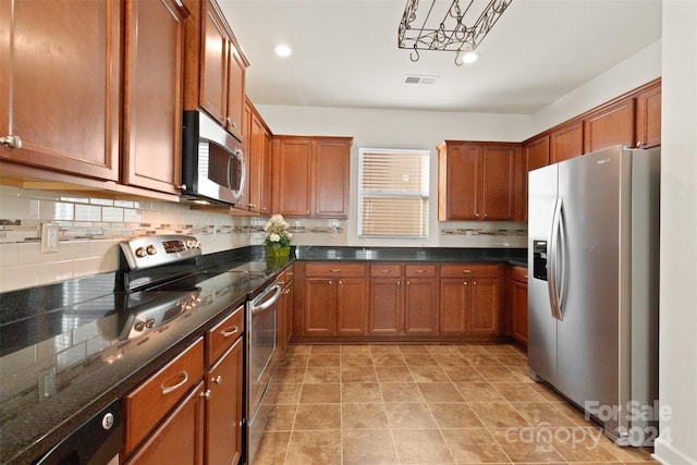 kitchen with backsplash, dark stone counters, decorative light fixtures, light tile patterned flooring, and stainless steel appliances