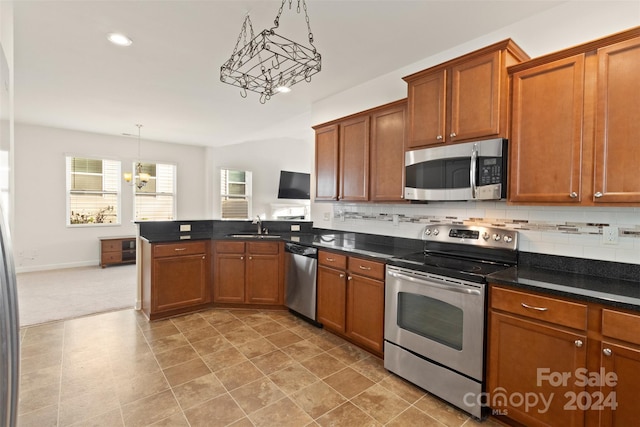 kitchen with hanging light fixtures, an inviting chandelier, backsplash, kitchen peninsula, and appliances with stainless steel finishes