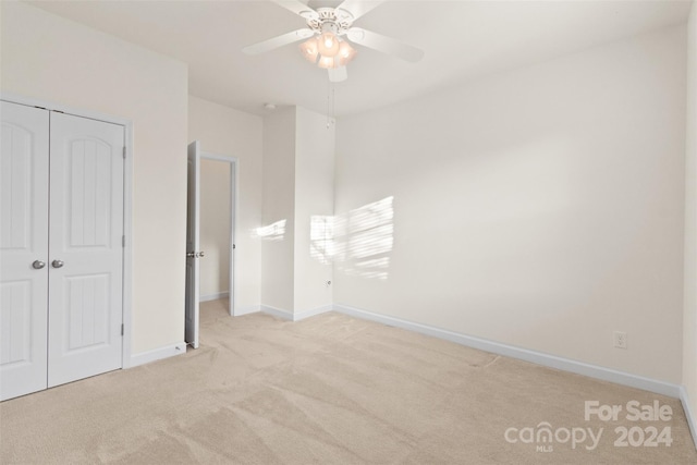 unfurnished bedroom with ceiling fan, light colored carpet, and a closet