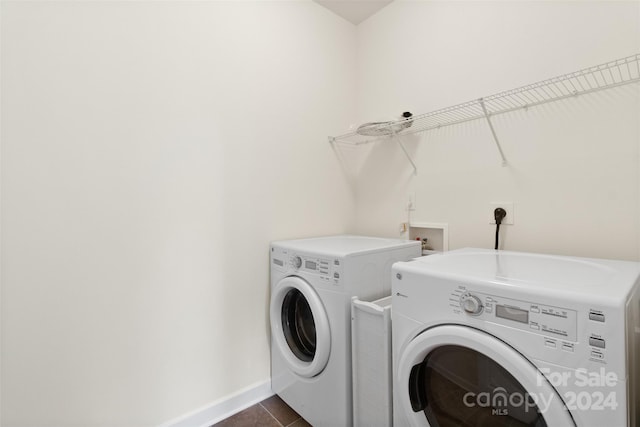 laundry room with washing machine and clothes dryer and dark tile patterned floors