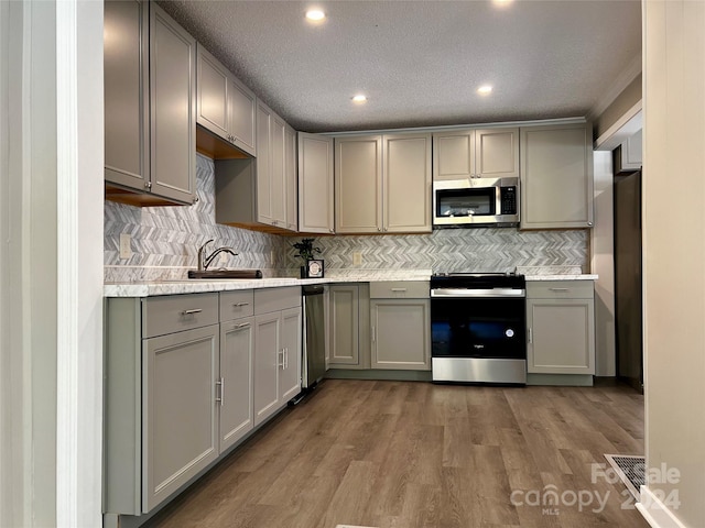 kitchen with gray cabinetry, stainless steel appliances, and wood-type flooring