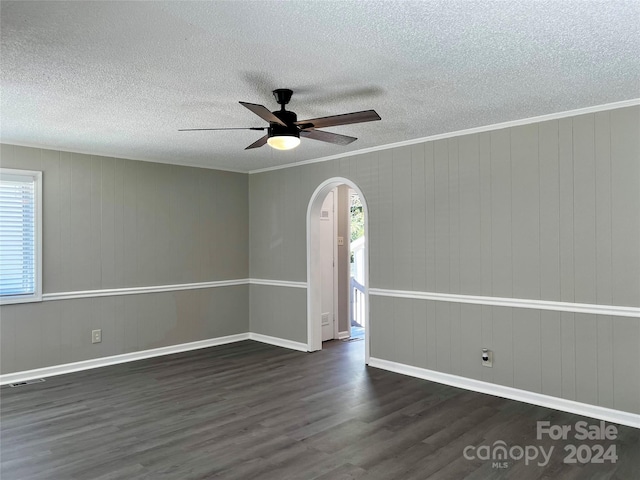 spare room featuring dark wood-type flooring, ceiling fan, ornamental molding, and a textured ceiling