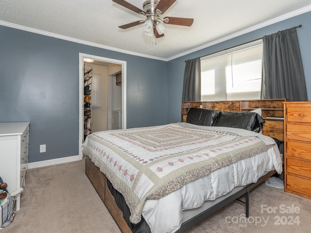 carpeted bedroom featuring ceiling fan, a textured ceiling, and ornamental molding