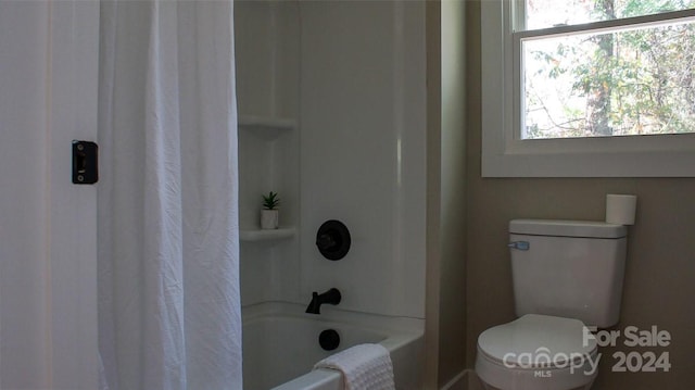 bathroom with shower / bath combination with curtain and toilet