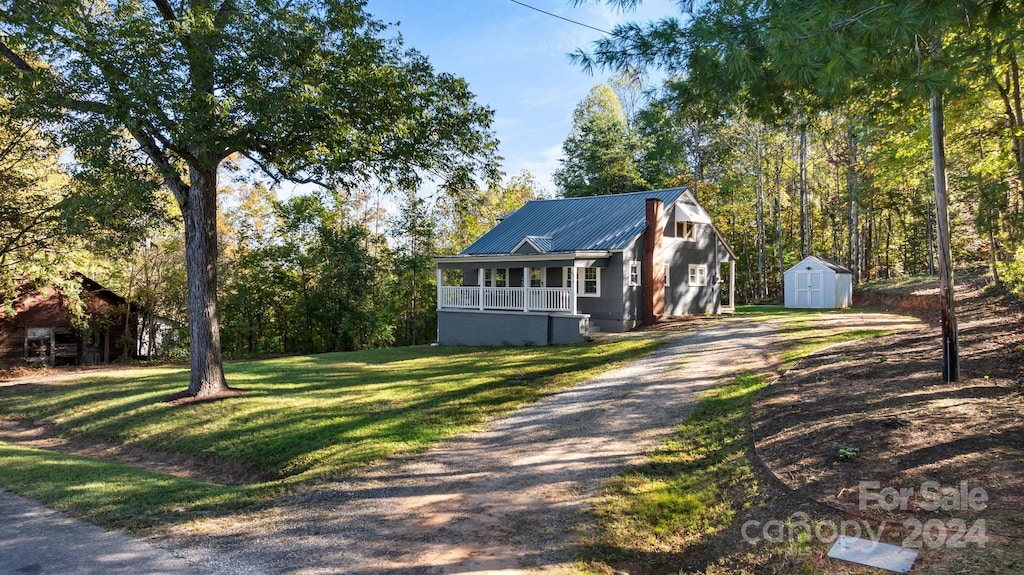 view of front of home with a storage unit, covered porch, and a front yard