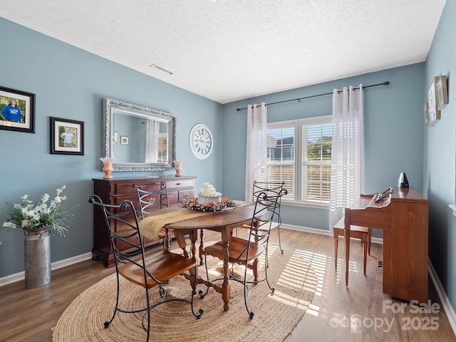 dining area with hardwood / wood-style flooring and a textured ceiling