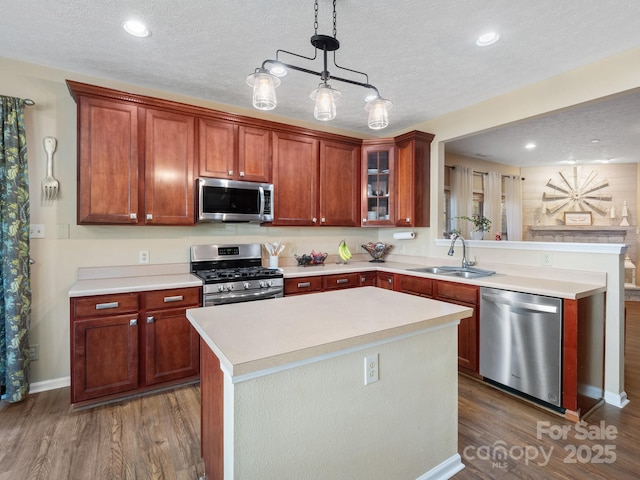 kitchen featuring sink, appliances with stainless steel finishes, a center island, dark hardwood / wood-style flooring, and decorative light fixtures