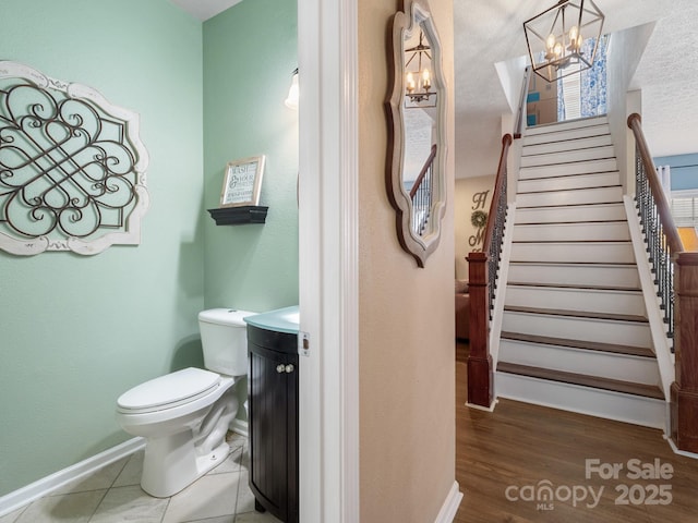 bathroom with vanity, toilet, a textured ceiling, and a notable chandelier