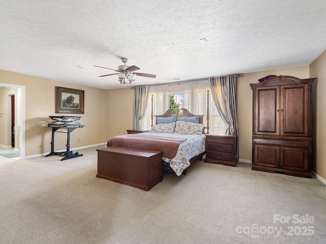 bedroom with a textured ceiling, light colored carpet, and ceiling fan