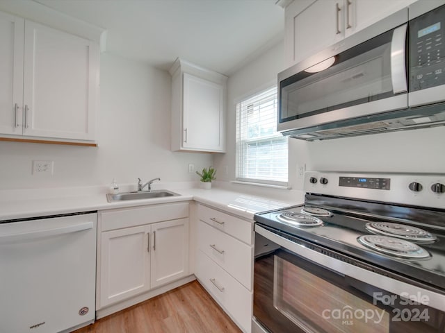 kitchen with stainless steel appliances, sink, light wood-type flooring, and white cabinets