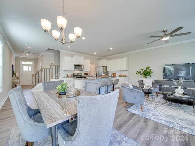 dining area featuring light hardwood / wood-style flooring, ornamental molding, and ceiling fan with notable chandelier