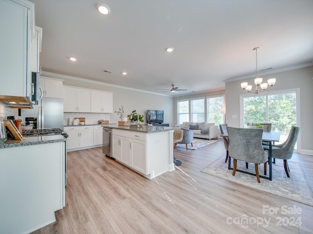 kitchen with a kitchen island, white cabinets, decorative light fixtures, and light wood-type flooring