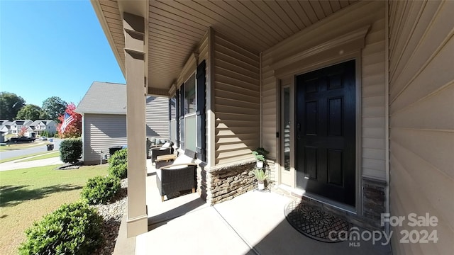 entrance to property with a yard, covered porch, and central AC unit