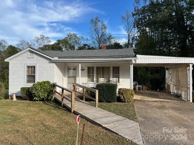 ranch-style home with covered porch, a front yard, and a carport