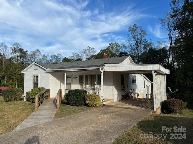 view of front of home with a front yard, covered porch, and a carport