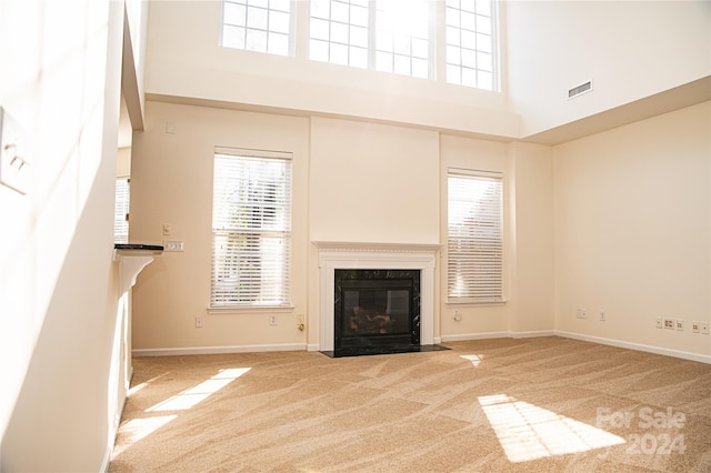 unfurnished living room featuring a high ceiling, carpet, and a premium fireplace