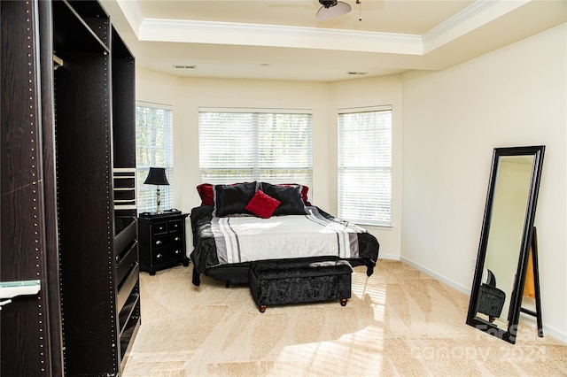 bedroom with a tray ceiling, multiple windows, light carpet, and ornamental molding