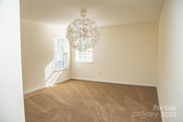 carpeted empty room with a chandelier