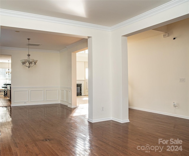 unfurnished room featuring dark hardwood / wood-style flooring, a notable chandelier, and crown molding