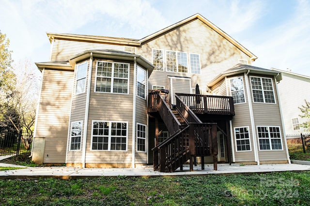 rear view of house with a deck, a lawn, and a patio