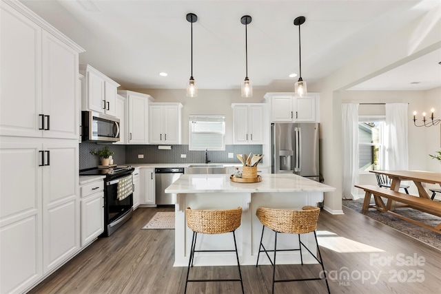 kitchen with sink, white cabinets, stainless steel appliances, and a kitchen island