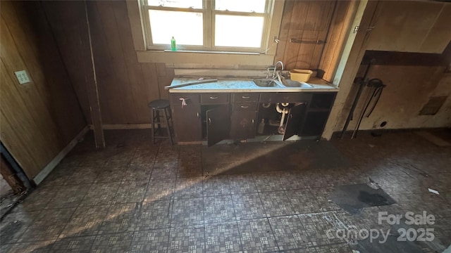 kitchen with light countertops, wood walls, and a sink