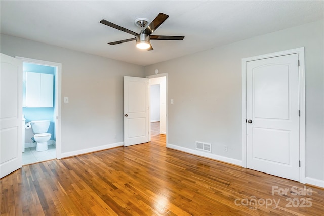 unfurnished bedroom with wood-type flooring, ceiling fan, and ensuite bath