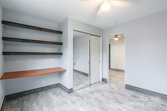 unfurnished bedroom featuring ceiling fan, built in desk, light hardwood / wood-style floors, and a closet