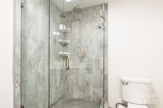 bathroom with toilet and a shower with shower door