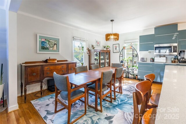 1166 Montford Dr, Charlotte, NC 28209 - dining room featuring light wood-style floors, crown molding, a chandelier, and baseboards