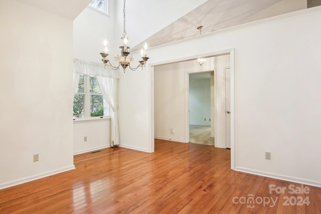 unfurnished room with a notable chandelier, hardwood / wood-style flooring, and high vaulted ceiling