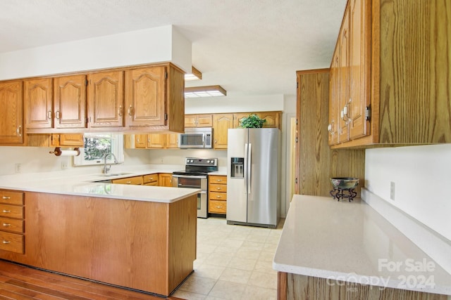 kitchen with a textured ceiling, appliances with stainless steel finishes, sink, and kitchen peninsula