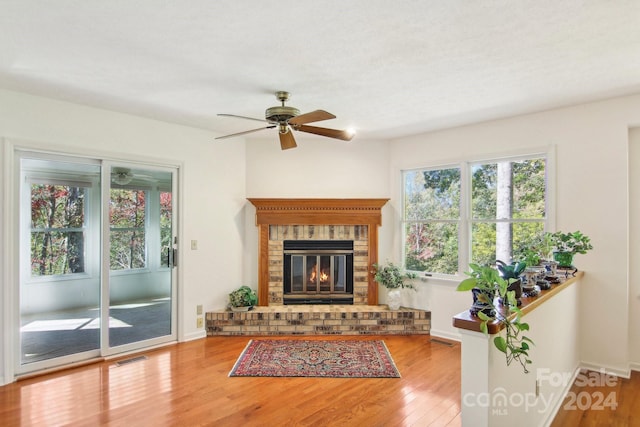 living room with hardwood / wood-style floors, a brick fireplace, and ceiling fan