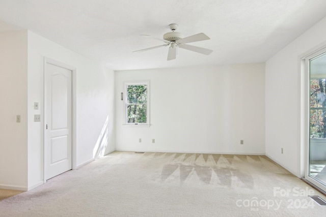 empty room with ceiling fan, a healthy amount of sunlight, and light colored carpet