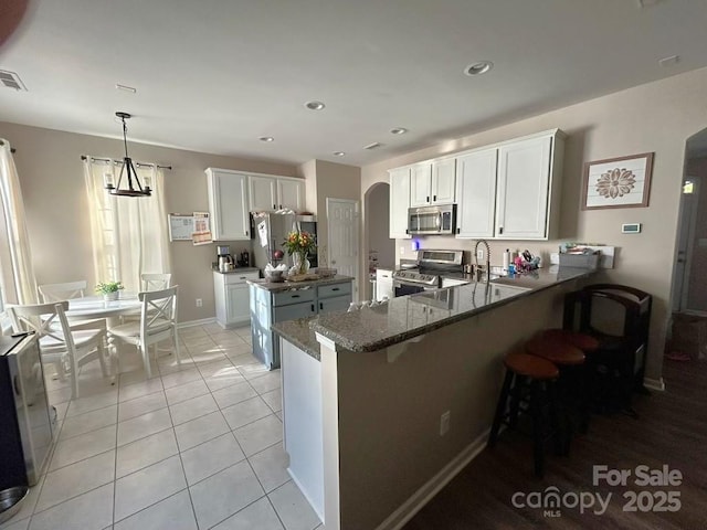 kitchen featuring kitchen peninsula, white cabinetry, light tile patterned floors, and stainless steel appliances