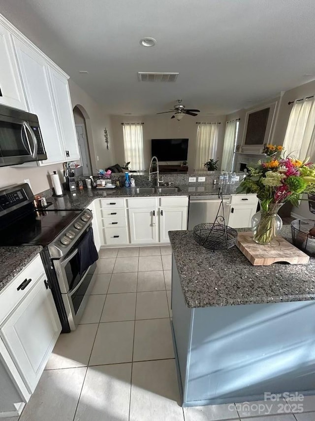 kitchen with kitchen peninsula, appliances with stainless steel finishes, ceiling fan, white cabinets, and light tile patterned flooring