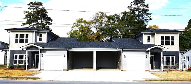 view of front facade with concrete driveway, an attached garage, and roof with shingles