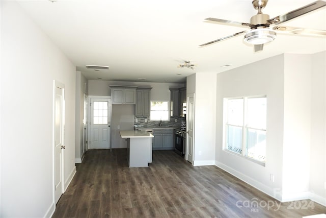 kitchen with sink, a center island, dark hardwood / wood-style flooring, gray cabinets, and tasteful backsplash