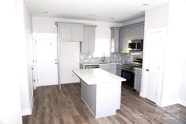 kitchen featuring backsplash, appliances with stainless steel finishes, gray cabinetry, a sink, and light countertops