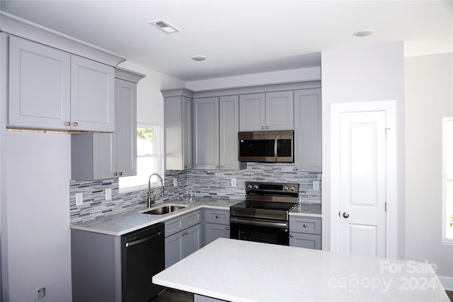 kitchen featuring gray cabinetry, appliances with stainless steel finishes, a sink, and visible vents