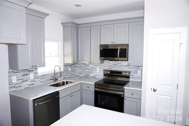 kitchen with backsplash, appliances with stainless steel finishes, sink, and gray cabinets