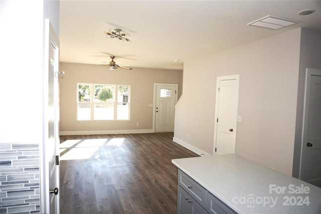 interior space featuring baseboards, a ceiling fan, and dark wood-type flooring