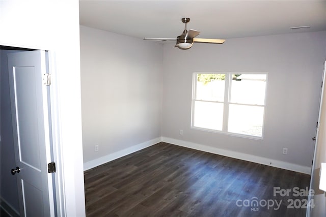 spare room with baseboards, a ceiling fan, and dark wood finished floors