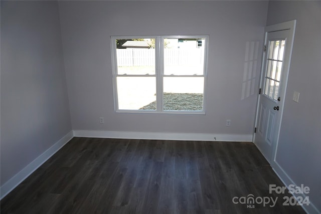 unfurnished room with baseboards and dark wood-type flooring
