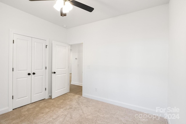 unfurnished bedroom featuring light carpet, a closet, and ceiling fan