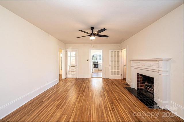 unfurnished living room with ceiling fan, a tiled fireplace, and hardwood / wood-style floors