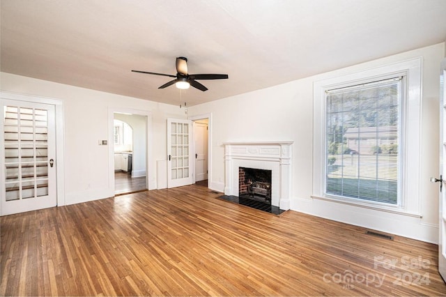 unfurnished living room with hardwood / wood-style floors, a brick fireplace, and ceiling fan