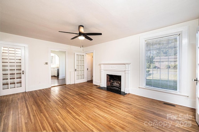 unfurnished living room with a brick fireplace, plenty of natural light, hardwood / wood-style floors, and ceiling fan