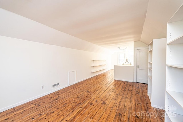 additional living space with hardwood / wood-style flooring and lofted ceiling